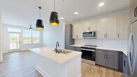 Located at 2600 Roby Corlew Lane in Murfreesboro, TN, this well-designed one-bedroom, one-bathroom residence offers a thoughtfully planned open-concept layout filled with natural light and contemporary finishes throughout. Light-toned wood-style flooring flows seamlessly across the entire space, creating a warm and cohesive aesthetic.

The combined dining, kitchen, and living area serves as the heart of the home. The kitchen is appointed with two-tone gray and white shaker cabinetry, a herringbone tile backsplash, white quartz countertops, and a full suite of stainless steel appliances including a range, over-the-range microwave, dishwasher, and refrigerator. A central island with an undermount sink and striking black pendant lighting above adds both functionality and style.

The living area benefits from large windows and a balcony door that opens to a private outdoor space with pleasant views of the surrounding area. A ceiling fan adds comfort to this bright, airy room.

The bedroom is a comfortable, well-lit retreat featuring a large window with outdoor views and access to two closets. The full bathroom offers a gray vanity with white quartz countertop, an undermount sink, black hardware accents, a framed mirror, and wood-style flooring. A dedicated utility room accommodates a stacked washer and dryer.