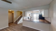 This two-floor residence offers a practical and well-organized layout across both levels. The main floor centers around an open-concept living and kitchen area, where light laminate wood flooring flows seamlessly underfoot. The kitchen is thoughtfully designed with white cabinetry, a white subway tile backsplash, dark countertops, stainless steel appliances including a dishwasher and microwave, and a peninsula with an integrated sink. Track lighting above the kitchen adds a functional accent, while a sliding glass door and adjacent window draw in natural light. A staircase with a wood banister connects the main floor to the upper level. Upstairs, multiple bedrooms feature light laminate flooring, neutral tones, ceiling fans with integrated lighting, and windows with blinds that allow for natural light. Built-in closet storage is present in at least one bedroom, adding practical utility. The home includes two bathrooms — one featuring a full tub-shower combination with clean white surround, and a second half-bath with an updated vanity featuring an undermount sink. Textured ceilings are consistent throughout, and the overall palette of soft neutrals creates a clean, move-in-ready atmosphere across the entire space.