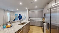 Located at 100 Watlington Dr in Calhoun, Georgia, this two-story home offers three bedrooms, three bathrooms, and a thoughtfully designed layout spread across two floors. The main level houses the combined kitchen and living area, an attached garage, a pantry, and a laundry room. The kitchen is a standout feature, showcasing gray shaker-style cabinetry, granite countertops with subtle veining, stainless steel appliances, and warm hardwood-style flooring that flows throughout the main living spaces. The open living room benefits from multiple windows that fill the space with natural light, and is finished with a ceiling fan overhead. A clean, neutral-toned hallway with hardwood-style flooring connects the main level, complemented by a staircase leading to the upper floor. Upstairs, three bedrooms provide comfortable accommodations, including a primary suite with its own bathroom and a walk-in closet fitted with wire shelving. The additional bedrooms are bright and well-proportioned, each with access to closet storage. The bathrooms throughout are finished in a crisp, clean style consistent with the home's modern aesthetic. The attached garage offers additional storage and convenience, completing this well-appointed home.