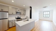 Located on the 11th floor at 933 McGee St in Kansas City, Missouri, this one-bedroom, one-bathroom unit offers a thoughtfully designed layout with contemporary finishes throughout. Warm light hardwood flooring flows seamlessly through every room, creating a bright and cohesive aesthetic.

The kitchen is a standout feature, equipped with stainless steel appliances including a refrigerator, microwave, and range. Grey shaker-style cabinetry pairs elegantly with a white subway tile backsplash, while the peninsula with a white quartz countertop and matte black sink faucet offers both prep space and a casual dining area.

The bedroom is a well-proportioned retreat featuring large, black-framed windows that frame city views and invite natural light. A ceiling fan with integrated lighting adds comfort, and the clean white walls provide a bright, airy atmosphere.

The bathroom is finished with a crisp, modern sensibility, featuring a glass-enclosed walk-in shower with light tile surround, a white vanity with matte black hardware, and in-unit laundry access, adding everyday convenience.

Throughout the unit, white walls and recessed lighting enhance the sense of openness. The overall ambiance is clean, modern, and functional — ideal for urban living in the heart of Kansas City.