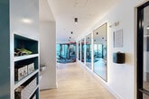 Located at 1400 Third Ave S in Birmingham, Alabama, this contemporary fitness center spans a single floor with a thoughtfully designed layout that accommodates a full range of exercise activities. The space is divided into distinct functional zones connected by a light-filled hallway, creating an organized and efficient flow throughout.

The entry hallway features light wood-style flooring, built-in open shelving for storage, a water fountain, and large framed mirrors that visually expand the space. Cylinder pendant lighting and clean white walls establish a bright, modern aesthetic from the moment you arrive.

The primary exercise room is an expansive, open-plan area bathed in natural light from floor-to-ceiling windows offering outdoor views of the Birmingham skyline. The cardio zone is outfitted with multiple treadmills, ellipticals, and stationary bikes, all facing the windows. The strength training area features a full multi-station rack system, a punching bag, a comprehensive dumbbell rack, and a variety of selectorized machines. Light hardwood-style flooring runs throughout this section.

A separate studio area offers carpeted flooring, wall-mounted mirrors, decorative woven pendant lights, and storage for kettlebells, medicine balls, and yoga mats — ideal for group fitness, stretching, or functional training. The overall ambiance is clean, bright, and professionally appointed.
