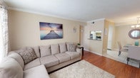 This single-floor, 2-bedroom, 2-bathroom residence offers a thoughtfully designed layout with a warm, neutral color palette throughout. The living room serves as the heart of the home, featuring rich hardwood flooring, crown molding, and natural light streaming through large windows dressed with sheer curtains. A pass-through window connects the living area to the kitchen, which is outfitted with white cabinetry, granite-style countertops, a double stainless steel sink, and a diagonal tile backsplash that adds a classic touch.

Both bedrooms are generously sized, carpeted for comfort, and include ceiling fans with light fixtures. Crown molding carries through each bedroom, maintaining a consistent, polished aesthetic. The primary bedroom benefits from natural light and walk-in closet access, while the second bedroom offers additional storage space. Each bathroom features a tiled tub-shower combination with diagonal-set wall tile, a toilet, and vanity with storage.

The overall layout, as seen in the 3D floorplan, flows efficiently from the entry through the living and dining areas into the private bedroom wing. The consistent use of neutral tones, crown molding, and quality finishes throughout creates a cohesive and inviting living environment well-suited for everyday comfort.