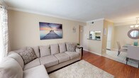 This single-floor, 2-bedroom, 2-bathroom residence offers a thoughtfully designed layout with a warm, neutral color palette throughout. The living room serves as the heart of the home, featuring rich hardwood flooring, crown molding, and natural light streaming through large windows dressed with sheer curtains. A pass-through window connects the living area to the kitchen, which is outfitted with white cabinetry, granite-style countertops, a double stainless steel sink, and a diagonal tile backsplash that adds a classic touch.

Both bedrooms are generously sized, carpeted for comfort, and include ceiling fans with light fixtures. Crown molding carries through each bedroom, maintaining a consistent, polished aesthetic. The primary bedroom benefits from natural light and walk-in closet access, while the second bedroom offers additional storage space. Each bathroom features a tiled tub-shower combination with diagonal-set wall tile, a toilet, and vanity with storage.

The overall layout, as seen in the 3D floorplan, flows efficiently from the entry through the living and dining areas into the private bedroom wing. The consistent use of neutral tones, crown molding, and quality finishes throughout creates a cohesive and inviting living environment well-suited for everyday comfort.
