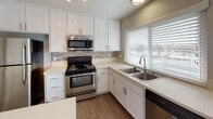 Located at 1231 W Francisquito Ave in West Covina, California, this single-floor residence offers a clean, updated interior with a cohesive neutral palette throughout. The kitchen is well-appointed with white shaker cabinetry, light countertops, a mosaic tile backsplash, and stainless steel appliances including a range, over-the-range microwave, and dishwasher. A double-basin sink is positioned beneath a window fitted with horizontal blinds, allowing natural light to fill the space. Wood-look flooring runs through the kitchen and extends into the open living area, which features a textured ceiling and a sliding glass door that leads to an outdoor balcony, bringing in additional natural light and views of the surrounding area. A peninsula counter connects the kitchen to the living space, creating a functional and open layout. A hallway leads to the bedroom, which is finished with plush carpeting, a textured ceiling, and a window with blinds. The bathroom includes a vanity with a white countertop, modern hardware, wood-look flooring, and a separate water closet with a soaking tub and shower combination. The space presents a move-in ready condition with modern updates and a practical single-level floor plan.