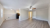 Located at 425 Mesa Ct in Little Rock, Arkansas, this single-floor residence offers a thoughtfully laid-out living space with a clean, updated aesthetic throughout. The open-concept living and dining area is finished with light gray laminate wood flooring, crisp white crown molding, and a textured ceiling, creating a bright and welcoming atmosphere. A ceiling fan with integrated lighting provides both comfort and illumination, while natural light filters in through windows to enhance the airy feel of the space.

The kitchen is efficiently designed with ample white cabinetry, light countertops, and a mosaic tile backsplash that adds a subtle decorative touch. It is equipped with black appliances, including a refrigerator, electric range, and under-cabinet range hood, along with a stainless sink and generous counter space for meal preparation.

The bedrooms continue the cohesive design with the same laminate flooring, neutral gray walls, textured ceilings, and ceiling fans. At least one bedroom features a walk-in closet, offering practical storage solutions. Natural light enters through windows dressed with blinds, contributing to a comfortable and functional environment.

The bathroom is finished in clean white tones, featuring a full tub and shower combination with tile surround. Throughout the residence, consistent finishes and a neutral color palette create a cohesive, move-in-ready space.