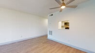 This single-floor unit is characterized by a clean, contemporary aesthetic carried consistently throughout its layout. Light wood-style flooring runs through the living areas, bedrooms, and bathrooms, creating a cohesive and airy feel. The open living area benefits from a ceiling fan with integrated lighting, crisp white walls, and a textured ceiling. A pass-through window connects the living space directly to the kitchen, enhancing the sense of openness. Access to an outdoor balcony is provided through a sliding glass door fitted with vertical blinds, allowing natural light to filter into the living area.

The kitchen is efficiently designed with white shaker-style cabinetry, light countertops, a subway tile backsplash, and stainless steel appliances including a range, microwave, and refrigerator. A six-panel interior door provides access to additional storage off the main corridor.

The bedrooms feature the same light flooring, with windows fitted with horizontal blinds. Closet space is provided via a dedicated walk-in-style closet with a full-length hanging rod. Two bathrooms serve the unit — one with a shower/tub combination and one with a stand-up shower — both finished with white tile surrounds, grey vanity cabinetry, and matching light flooring.