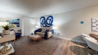 This ground-floor unit in Kent, Washington offers a well-organized, single-level layout designed for comfortable everyday living. The living area features a combination of wood-style hard flooring and plush carpet, with a sliding glass door that allows natural light to filter in. Neutral gray walls and a textured ceiling carry throughout the space, providing a cohesive backdrop across all rooms.

The kitchen is thoughtfully appointed with white upper cabinetry, dark lower cabinetry, quartz countertops, a classic subway tile backsplash, and an electric range. A sliding door off the kitchen provides access to additional storage. The hallway connects the main living spaces to the bedrooms, and is finished with wood-style flooring and ceiling lighting.

The primary bedroom features plush carpet, a window with blinds for natural light and privacy, and a baseboard heater. A second bedroom, also carpeted, includes a window with horizontal blinds and ample room for furnishings. The bathroom offers a full tub-and-shower combination with a curtain, toilet, and overhead storage. Overall, the unit presents a clean, neutral aesthetic suited to a variety of lifestyles.