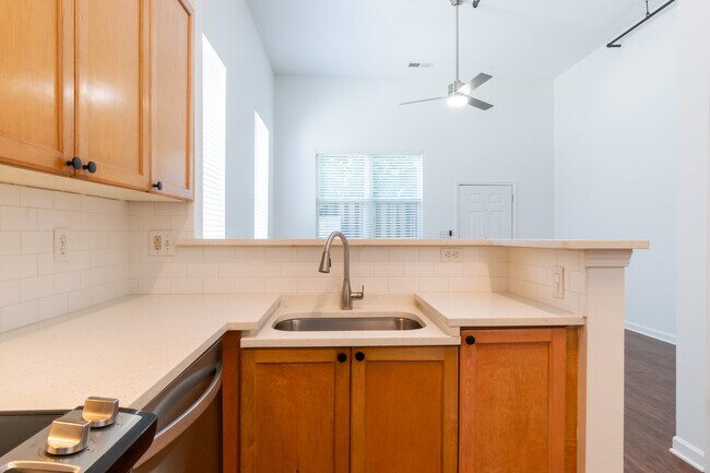 Hermosa cocina con encimeras de piedra, electrodomésticos renovados, protector contra salpicaduras de azulejos tipo metro y asientos de barra. - Westview Lofts