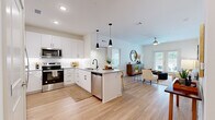 Located at 411 Sage Rd N in White House, Tennessee, this single-story 2-bedroom, 2-bathroom home offers a thoughtfully designed open-concept layout that seamlessly connects the kitchen, dining, and living areas. The kitchen is a standout feature, showcasing crisp white shaker cabinetry, granite countertops, stainless steel appliances, a center island with bar seating, and sleek black pendant lighting overhead. Light wood-look flooring flows throughout the main living areas, enhancing the bright, airy atmosphere. The living room is bathed in natural light from a set of French doors that open to an outdoor patio, offering pleasant views of the surrounding greenery. The primary bedroom is a comfortable retreat with plush carpeting, natural light from large windows, and access to a spacious walk-in closet outfitted with wire shelving. The second bedroom is equally well-sized with its own walk-in closet. Both bathrooms feature granite-topped vanities, white cabinetry, and clean tile work. A ceiling fan in the living area and recessed lighting throughout add to the home's functional, modern appeal. The overall ambiance is clean, contemporary, and move-in ready.