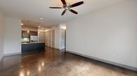 Located at 5151 Hidalgo St in Houston's Galleria area, this one-bedroom, one-bathroom residence offers a thoughtfully designed layout across a single floor. Polished concrete floors run throughout the main living areas, lending a contemporary, urban aesthetic that is both stylish and durable. The open-concept kitchen is a standout feature, showcasing rich dark cabinetry, a mosaic tile backsplash, stainless steel appliances including a gas range, microwave, and French-door refrigerator, as well as a large island with a sleek white countertop and pendant lighting overhead — ideal for both cooking and casual dining. The spacious living area benefits from generous natural light through large windows and a ceiling fan overhead. The bedroom is carpeted for comfort and offers direct access to a private balcony through French doors flanked by windows, providing pleasant outdoor views. A dedicated walk-in closet features built-in shelving on multiple walls, offering abundant organized storage. The full bathroom is well-appointed with a dual-sink vanity featuring white countertops and gray cabinetry, a soaking tub with tiled surround, and polished concrete flooring that carries the home's modern design language throughout.
