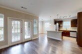 Located at 4400 College Park Dr in Conroe, TX, this single-floor 2-bedroom, 2-bathroom residence offers a thoughtfully designed open-concept layout with modern finishes throughout. Rich hardwood-style flooring flows seamlessly across the living, dining, and kitchen areas, anchored by crown molding and neutral tones that create a bright, welcoming atmosphere.

The combined living, dining, and kitchen space serves as the heart of the home. The kitchen features dark espresso cabinetry, granite-style countertops, a subway tile backsplash, stainless steel appliances including a refrigerator and dishwasher, and a central island with pendant lighting. French doors flood the living area with natural light and provide access to a private patio.

Both bedrooms are generously sized, each equipped with ceiling fans and large windows that bring in ample natural light. The primary bedroom includes a well-organized walk-in closet with built-in shelving and dual hanging rods. The two bathrooms are finished with granite-topped dark wood vanities and tiled shower-tub combos.

A dedicated built-in workspace with granite countertop and open shelving adds functional versatility. The unit also includes an in-home laundry area, multiple closets for storage, and hallways connecting each space efficiently.