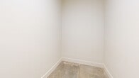 This compact utility space at 701 Downsby Ln in Woodstock, Georgia, offers a clean, minimalist layout ideal for functional storage or utility purposes. The room is accessed through a classic three-panel white door accented with sleek matte black hinges and a matching lever-style door handle, adding a modern touch to the entryway. Inside, the walls are finished in a crisp, bright white that reflects light evenly throughout the space, creating a clean and open feel despite the room's modest footprint. White baseboards run along the perimeter, providing a tidy, finished appearance. The floor is currently an unfinished concrete surface, suggesting the space may be in a pre-finished or ready-to-customize state, offering flexibility for a future flooring installation of the occupant's choice. The room's simple, uncluttered design makes it well-suited for use as a laundry room, storage closet, or utility area. Overall, the space presents a functional and neatly constructed room with thoughtful finishing details and clear potential for customization to meet a variety of needs.