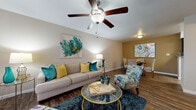 This single-floor residence offers a thoughtfully designed layout that balances comfort and functionality throughout. The open-concept living and dining area serves as the heart of the home, featuring warm wood-style flooring, a ceiling fan with integrated lighting, and neutral-toned walls that create a welcoming ambiance. The living space flows naturally into a dedicated dining area, making it ideal for both relaxing and entertaining.

The galley-style kitchen is efficiently arranged with dark cabinetry lining both sides, granite-style countertops, a double sink, and white appliances including a range and refrigerator. The wood-style flooring continues here, adding cohesion to the shared living spaces.

The bedrooms are carpeted for comfort, with the primary bedroom offering generous natural light through a large window dressed with sheer curtains. The room provides ample space for full-size furnishings and features neutral wall tones that contribute to a calm, restful atmosphere.

The bathroom is well-equipped with a dark vanity cabinet topped with a speckled granite-style countertop, a large wall mirror, and a shower-tub combination. Wood-style flooring ties the bathroom aesthetic to the rest of the home.

Overall, this residence presents a cohesive and comfortable living environment with consistent finishes and a practical, well-connected floor plan throughout.