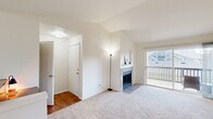 Located at 308 NE Autumn Rose Way in Hillsboro, Oregon, this single-floor, 2-bedroom, 2-bathroom home offers a well-organized layout designed for comfortable living. The living room serves as the centerpiece of the home, featuring soaring vaulted ceilings that lend an open, airy feel, a tile-surround fireplace, and a sliding glass door that opens to a private balcony with neighborhood views. Plush carpeting flows throughout the living areas and bedrooms, while warm hardwood-style flooring accents the kitchen, hallway, and bathrooms. The kitchen is equipped with white cabinetry with wood trim accents, white appliances including a range and refrigerator, and a peninsula breakfast bar that connects seamlessly to the living room. The primary bedroom is generously proportioned, featuring vaulted ceilings, a walk-in closet, and natural light. The second bedroom also benefits from abundant natural light through large windows. Both bathrooms include vanities with countertop space and hardwood-style flooring; the full bathroom features a tub/shower combination. Two closets provide ample storage throughout the home, and a central hallway connects all rooms efficiently.