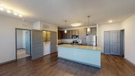 This single-floor residence in Jacksonville, FL (32246) offers a thoughtfully designed open-concept layout with contemporary finishes throughout. The kitchen is a standout feature, showcasing dark wood-tone cabinetry, granite countertops, and a full suite of stainless steel appliances including a range, microwave, and refrigerator. A large center island with an undermount sink and pendant lighting above serves as both a functional workspace and a natural gathering point. Dark hardwood-style flooring runs throughout the main living areas, adding warmth and continuity to the open floor plan. The spacious living area is illuminated by natural light from windows with blinds and features a ceiling fan overhead. Bedrooms are carpeted for comfort, each equipped with ceiling fans and windows that bring in natural light. The primary bathroom includes a glass-door shower, granite-top vanity, and wood-style flooring, while the secondary bathroom offers a full tub-shower combo with tile surround. A dedicated in-unit laundry area with a full-size washer and dryer is conveniently accessible from the main living space. The overall ambiance is clean, modern, and move-in ready, reflecting a practical yet stylish approach to everyday living.