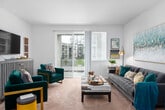 This thoughtfully designed single-floor residence offers a cohesive layout that balances comfort and functionality across its key living spaces. The living room serves as the heart of the home, featuring plush carpeting, generous natural light, and a sliding glass door that opens onto a private balcony with views of the surrounding community. The space accommodates a full seating arrangement, making it ideal for both relaxing and entertaining. The galley-style kitchen is outfitted with dark cabinetry, light countertops, and stainless steel appliances, offering ample storage and a practical workflow along its corridor layout, with wood-look flooring underfoot. Adjacent to the kitchen, a compact dining nook provides an intimate setting for meals, accentuated by neutral walls that complement any décor. The primary bedroom offers a calm, carpeted retreat with soft neutral tones, while the second bedroom benefits from a large window that frames views of greenery and neighboring rooftops, filling the room with natural light. The full bathroom features wood-look flooring, a tub-shower combination, dark vanity cabinetry with a white countertop, and a wide mirror above the sink, creating a clean and functional space. Throughout, the residence maintains a consistent, inviting aesthetic with neutral walls and warm finishes.