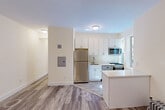 Located at 125 Magnolia Avenue in Jersey City, NJ, this two-bedroom residence offers a well-organized single-floor layout designed for comfortable urban living. The kitchen is a standout feature, showcasing white shaker-style cabinetry, quartz countertops, a peninsula with additional counter space, and a full suite of stainless steel appliances including a gas range, dishwasher, microwave, and refrigerator. Natural light filters in through a window above the sink, and the wood-look luxury vinyl flooring ties the kitchen seamlessly into the adjacent living and hallway areas. Both bedrooms are finished with the same warm flooring and soft, neutral wall tones. The primary bedroom benefits from dual windows framing views of the surrounding Jersey City streetscape, a built-in closet, and a classic cast-iron radiator. The second bedroom also features a window with neighborhood views, a closet, and its own radiator, providing consistent warmth. Each bedroom is accessed via a connecting hallway that keeps the layout efficient and private. Throughout the residence, clean white trim, panel-style doors, and understated finishes create a bright, move-in-ready aesthetic well-suited to city living.