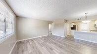 Located at Seaford Circle in Tampa, FL, this two-bedroom, one-bathroom residence offers a practical and well-appointed single-floor layout. Light-toned luxury vinyl plank flooring runs throughout, lending a clean, cohesive look to every room. The open-concept living area flows naturally into the kitchen, which features white shaker-style cabinetry, granite-look countertops, a peninsula with bar seating, stainless steel appliances, and a dedicated pantry closet. A textured ceiling adds subtle character throughout the living spaces. The primary bedroom is generously proportioned and includes a sliding double-door closet, while the second bedroom also benefits from natural light through a window with exterior views of the surrounding greenery. Both bedrooms share a full bathroom appointed with a white vanity, quartz-look countertop, a wall-mounted mirror, and a full tub-shower combination. A hallway connects the bedrooms and bathroom, with an additional closet providing extra storage. The unit is further enhanced by neutral warm-beige walls, white trim, and multiple windows that invite natural light throughout. A private entry door with a front-facing window completes this move-in-ready Tampa residence.