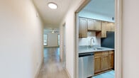 This two-story home offers three bedrooms and two bathrooms distributed across two well-proportioned floors of nearly equal size. The main floor features a living room with light wood-style flooring, a ceiling fan, and natural light from multiple windows. Adjacent to the living area, the kitchen is outfitted with warm-toned wood cabinetry, granite countertops, a classic subway tile backsplash, and a full suite of stainless steel appliances including a refrigerator, dishwasher, and electric range. A hallway connects the main living areas and leads to the staircase.

The upper floor houses the bedrooms, including a generously sized primary bedroom with a walk-in closet featuring built-in shelving. The bedrooms are carpeted and include ceiling fans, while the bathrooms echo the kitchen's design with matching granite-topped wood vanities and light wood-style flooring. One bathroom includes a bathtub with a tub surround. Throughout the home, a neutral color palette of soft whites and beiges, textured ceilings, and consistent light-toned flooring create a cohesive and practical living environment.