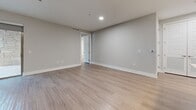 Located in Austin, TX, this well-appointed 2-bedroom, 2-bathroom residence offers a thoughtfully designed single-floor layout that balances comfort and modern style. Wood-style flooring flows throughout, complementing the neutral gray tones of the walls and creating a cohesive, clean aesthetic. The open-concept kitchen and living area serves as the heart of the home, featuring a generous island with white countertops, gray cabinetry, stainless steel appliances, stylish pendant lighting, and recessed lighting overhead. The living room extends naturally to a private balcony through sliding glass doors, where a wood-ceiling overhang, stone accent walls, and horizontal metal railings frame peaceful views of mature trees and the surrounding community. Both bedrooms are well-sized, each equipped with a ceiling fan, wood-style flooring, and windows that invite natural light. The primary bedroom includes a spacious walk-in closet with built-in shelving and hanging rods, as well as an en-suite bathroom featuring a glass-enclosed shower, sleek vanity, and tile flooring. A second walk-in closet provides additional storage. A connecting hallway ties all spaces together efficiently, completing this functional and contemporary Austin residence.