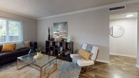 This single-floor residence offers a thoughtfully designed layout with a cohesive aesthetic carried throughout. Rich, dark hardwood-style flooring runs through the main living areas, anchoring the warm yet contemporary feel of the home. The living room features crown molding, a textured ceiling, and ample space for relaxed seating arrangements. A separate sitting area provides additional flexibility, complete with a closet housing a stacked in-unit washer and dryer. The kitchen is well-equipped with dark espresso cabinetry, black appliances including a range, microwave, and dishwasher, complemented by a decorative tile backsplash and a double-basin sink beneath a bright window. A breakfast bar with seating connects the kitchen to the dining area, where a ceiling fan with light fixture adds both function and style to the space. The bedroom features wood-style flooring, a textured ceiling, and a window allowing natural light to filter in, creating a calm and restful atmosphere. The bathroom is finished with dark wood vanity cabinetry, granite-style countertops, tile flooring, and a full tub-shower combination. Throughout the home, neutral gray walls and white trim create a clean, modern backdrop.