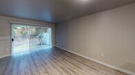 Located at 11305 SE Kent Kangley Rd in Kent, Washington, this two-story residence offers a well-organized layout spread across two levels connected by a carpeted staircase. The main level features a living area anchored by a corner fireplace with a clean white mantle surround, complemented by wood-look vinyl flooring that runs throughout the common areas. A sliding glass door provides access to an outdoor patio space, bringing natural light into the living room. The kitchen is outfitted with white shaker-style cabinetry, stone-look countertops, a black electric range with an over-the-range microwave, a dishwasher, and a sink — offering a functional and modern cooking space. A convenient half bathroom is also located on the main level. Upstairs, the carpeted bedrooms offer a comfortable retreat, each featuring vertical blinds, windows with natural views, and baseboard heating. The bedrooms include closets with sliding doors and built-in hanging rods for storage. Two full bathrooms serve the upper level, one featuring a walk-in shower with glass enclosure and a wide vanity mirror, and another with a shower-tub combination and wood-look flooring. The neutral color palette throughout creates a clean, move-in ready atmosphere.