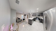 This well-appointed 2-bedroom, 2-bathroom residence offers a thoughtfully designed single-floor layout with a seamless open-concept living space. Consistent marble-look porcelain tile flooring flows throughout, lending a clean, modern aesthetic to every room.

The entrance leads into a bright, open living and dining area that connects directly to the kitchen, creating an ideal space for entertaining. The kitchen is outfitted with dark wood-grain cabinetry, crisp white quartz countertops, stainless steel appliances including a range, microwave, and dishwasher, and a peninsula with pendant lighting above. A pantry provides additional storage. The dining area sits adjacent, and a balcony extends the living space outdoors.

The primary bedroom is generously sized, featuring a ceiling fan, a large window for natural light, a closet, and access to a well-finished bathroom with marble-look tile walls and a glass-enclosed shower. The second bedroom is equally comfortable with its own closet. Both bathrooms reflect a cohesive, upscale design.

A dedicated laundry room houses a full-size washer and dryer, adding everyday convenience. The layout also includes a second closet for additional storage. Overall, the space presents a contemporary, move-in-ready environment with refined finishes throughout.