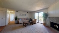 This single-floor residence offers a well-organized layout that balances comfort and functionality across multiple distinct living spaces. The living room serves as the heart of the home, featuring plush wall-to-wall carpeting, a textured ceiling, and a striking brick fireplace that anchors the room. A large sliding glass door floods the space with natural light and opens directly onto a private balcony, offering pleasant outdoor views. The open feel of the living area makes it well-suited for both relaxing and entertaining.

The kitchen is efficiently designed with warm oak cabinetry, light countertops, wood-look luxury vinyl flooring, and white appliances including a range, refrigerator, and dishwasher. Adjacent to the kitchen, the dining area continues the wood-look flooring and features a convenient built-in storage closet with shelving, adding practical utility to the space.

The bedroom is generously proportioned, finished with soft carpeting, a natural light-admitting window with blinds, and a walk-in closet. The space accommodates large furniture comfortably. Two bathrooms serve the residence — one featuring a full soaking tub and the other a standalone shower stall — both finished in clean, bright white.