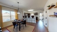 Located at 1016 Carpenter Blvd in Blacksburg, Virginia, this multi-story residence spans three floors and offers a thoughtfully designed layout with quality finishes throughout. The open-concept main living area features rich hardwood-style flooring, crown molding, and generous natural light from multiple windows dressed with warm curtains. The living room provides a welcoming gathering space with a ceiling fan and ample room for comfortable seating. The kitchen is a standout feature, showcasing dark espresso cabinetry, granite countertops, stainless steel appliances including a range, microwave, and dishwasher, along with a peninsula bar with seating that flows seamlessly into the adjacent dining area. Upper floors transition to soft carpeting, where the bedrooms offer a quiet retreat. Each bedroom is generously sized, featuring ceiling fans and walk-in closets with built-in shelving. The bathrooms maintain the home's refined aesthetic with dark wood vanities, granite countertops, and tile flooring. Carpeted hallways with raised-panel doors and decorative wall art add to the polished interior feel. The overall ambiance of the residence is warm and modern, balancing practical functionality with comfortable, upscale living throughout all three floors.