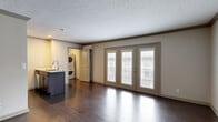 This efficiently designed apartment at 1019 Everett Ave in Louisville, Kentucky offers a well-appointed single-floor layout that maximizes every square foot. The main living area is bright and open, anchored by rich dark hardwood flooring and a textured ceiling. A set of full-length French doors floods the space with natural light and provides access to an outdoor balcony area, creating an airy, connected feel.

The kitchen is a standout feature, showcasing dark espresso cabinetry, a granite-topped island with an undermount sink, stainless steel appliances including a range, microwave, and refrigerator, and a classic subway tile backsplash. Recessed and flush-mount lighting add warmth to the space, while crown molding throughout lends a refined architectural detail.

The bathroom is cleanly finished with light tile flooring, a dark vanity topped with granite, an undermount sink, and a tiled tub-shower combination accented by a vertical mosaic tile inset for a contemporary touch.

A dedicated laundry closet houses a stacked washer and dryer unit along with wire shelving, providing practical in-unit convenience. The cohesive use of dark hardwood flooring, granite surfaces, and neutral tones throughout gives this apartment a consistent, modern aesthetic.