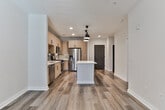 Located on Pearl Street SE in Atlanta's dynamic 30316 zip code, this single-floor residence showcases a contemporary design aesthetic with thoughtfully selected finishes throughout. The open-concept kitchen serves as the heart of the space, featuring light wood-grain cabinetry with matte black hardware, a quartz countertop island illuminated by a pendant light, and a gray subway tile backsplash. A full suite of stainless steel appliances—including a gas range, built-in microwave, dishwasher, and French door refrigerator—completes the well-equipped cooking area. Wood-look luxury vinyl plank flooring runs throughout the main living and kitchen areas, adding warmth and cohesion to the space. The bathroom mirrors the home's modern sensibility, offering a wood-toned vanity with quartz countertop, a large black-framed mirror, matte black fixtures, and a well-lit vanity bar. The bedroom features plush carpet flooring, a ceiling fan, and a window fitted with blinds that allows natural light to filter in. Recessed lighting and ceiling fans contribute to a comfortable, well-lit environment throughout this neatly designed Atlanta residence.