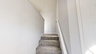Located at 161 Peters Dr in Groton, Connecticut, this three-floor home offers a well-organized layout across its three levels. The ground floor houses a spacious garage with an epoxy-coated concrete floor and a utility room, providing practical storage and functional space. The main living level features an open, light-filled living area with light wood-look flooring, large sliding glass doors, and multiple windows that frame views of the surrounding wooded landscape. The kitchen is a standout, featuring white shaker-style cabinetry with matte black hardware, a classic subway tile backsplash, white quartz countertops, a undermount sink, and a full suite of stainless steel appliances. The upper floor is home to three carpeted bedrooms, including a generously sized primary bedroom bathed in natural light from dual windows overlooking the outdoors. The two bathrooms are finished with brushed nickel fixtures — one featuring a tiled tub-shower surround with a built-in niche and wood-look vinyl flooring, and the other offering a clean vanity with mirror. Carpeted staircases with white railings connect all three floors. Throughout, the home maintains a clean, neutral palette with gray walls and white trim, creating a bright and cohesive atmosphere.