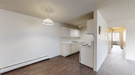 Located in Lakewood, Colorado, this single-floor, 3-bedroom, 2-bathroom unit offers a practical and well-organized layout. Dark hardwood-style flooring flows consistently throughout, providing a cohesive look across all rooms. Textured ceilings are present throughout the space.

The kitchen is designed in a galley configuration, featuring white cabinetry with ample upper and lower storage, light countertops, a single-basin sink, a coil-burner electric range, and a full-size refrigerator. Track lighting illuminates the workspace, and a pendant light fixture adds a functional accent near the open dining area adjacent to the kitchen.

The living room is generously sized, featuring large windows with vertical blinds that allow natural light to fill the space. A wall-mounted air conditioning unit and baseboard heating provide year-round climate control.

The primary bedroom is a well-proportioned room with a window overlooking the outdoors, an open closet with a hanging rod, and direct access to one of the two bathrooms. The additional bedrooms are comparably sized, each with windows and baseboard heating.

Both bathrooms are clean and functional, each featuring a tub-shower combination with tiled surrounds, light wood-toned vanities, and hardwood-style flooring. A hallway connects the bedrooms and bathrooms, completing the efficient floor plan.