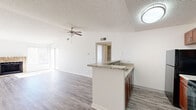 Located at 7555 E Warren Dr in Denver, CO, this one-bedroom, one-bathroom unit offers a well-planned single-floor layout with a comfortable and functional living space. The open-concept living and dining area is a standout, featuring vaulted ceilings, a ceiling fan, and light gray wood-style flooring that runs throughout the main areas. A classic brick wood-burning fireplace serves as the focal point of the living room, complemented by large windows and a sliding glass door that floods the space with natural light and provides access to a private balcony with outdoor views.

The kitchen is thoughtfully designed with rich wood cabinetry, granite-style countertops, a tiled backsplash, a breakfast bar peninsula, and black appliances including a refrigerator, electric range, and over-the-range microwave. The bedroom is generously sized, featuring plush carpeting, a large window with outdoor views, and direct access to a dedicated closet. The full bathroom is well-appointed with a wood vanity, granite-style countertop, a lighted mirror, and a shower-tub combination. Additional conveniences include an in-unit laundry area and a hallway connecting all spaces for easy flow throughout the home.