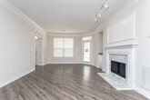 Located at 6115 Abbotts Bridge Rd in Johns Creek, Georgia, this single-floor residence offers a thoughtfully designed layout with a blend of comfort and style. The open living and dining area serves as the heart of the space, showcasing rich hardwood-style flooring, track lighting, and a striking marble-surround fireplace as a focal point. Built-in shelving flanks the fireplace, adding both character and function. The kitchen features white cabinetry, granite-style countertops, a breakfast bar pass-through, and black appliances, with convenient access to an in-unit laundry area. The bedrooms are carpeted and bathed in natural light, each highlighted by elegant tray ceilings with crown molding. The primary bedroom includes a spacious walk-in closet and direct access to the hallway. One bedroom features French doors that open to the outdoors, adding a bright, airy feel. The bathrooms are well-appointed with white cabinetry, granite-style countertops, large vanity mirrors, and a tub-shower combination. Throughout the space, neutral tones and consistent finishes create a cohesive, inviting ambiance ideal for everyday living.