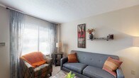 Located at 3444 Tivoli Ct in Columbus, Ohio, this multi-level home spans three floors and offers a well-organized layout with a variety of functional living spaces. The main level features a carpeted living room filled with natural light from large windows dressed with sheer drapes and horizontal blinds. It opens seamlessly into a dedicated office or dining area illuminated by a pendant light fixture. The kitchen is efficiently designed in a U-shaped configuration, featuring warm oak cabinetry, light countertops, a double-basin sink, and white appliances including a range and dishwasher, complemented by easy-care flooring. The upper level hosts multiple carpeted bedrooms, each offering closet storage and neutral tones. One bedroom includes an adjoining full bathroom with a tiled tub-shower combination, wood-trimmed vanity, and tile flooring. A second upper-level bedroom features its own closet and direct access to a hallway bathroom. The lower level provides a finished recreation room distinguished by a painted brick accent wall and plush carpeting, offering a cozy, versatile gathering space. Throughout all three floors, the home maintains a consistent palette of neutral walls, wood-trimmed doors, and carpet flooring, creating a cohesive and comfortable living environment.