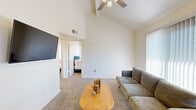 Located at 4250 E Foothills Dr in Sierra Vista, Arizona, this 2-bedroom, 3-bathroom residence offers a well-organized single-floor layout designed for comfortable everyday living. The living room immediately impresses with its soaring vaulted ceiling and a ceiling fan overhead, creating an airy, open atmosphere. Large windows with vertical blinds flood the carpeted space with natural light and provide views of the surrounding greenery. The galley-style kitchen is efficiently designed, featuring white cabinetry, dark granite-style countertops, a double basin sink, and stainless steel appliances including a range and refrigerator, all set over clean hardwood-style flooring. The primary bedroom continues the vaulted ceiling theme, complete with a ceiling fan, a sliding door closet, and a window framing outdoor views. The second bedroom is cozy and well-lit, also featuring a ceiling fan, a closet, and a window with natural light. Three bathrooms serve the home, including one with a clean, white-tiled walk-in shower. Soft carpeting runs throughout the bedrooms and living areas, contributing to the home's warm and neutral aesthetic. The overall design is bright, clean, and functional, making efficient use of the available space.