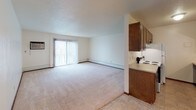 Located at 400 S Sneve Ave in Sioux Falls, South Dakota, this single-floor unit offers a practical and comfortable layout suited for everyday living. The open living area is generously sized, featuring plush wall-to-wall carpeting, a textured ceiling, and a ceiling fan with integrated lighting. A large sliding glass door floods the space with natural light and provides access to the outdoors, making the living area feel bright and airy. The kitchen is designed for efficiency, featuring rich dark wood cabinetry that lines both upper and lower sections, a double-basin sink, tile flooring, and white appliances including an electric range and refrigerator. A ceiling fan is also present in the kitchen area. Adjacent to the kitchen is an entry area with tile flooring, a front door with a sliding closet for storage, and a ceiling fan overhead. The bathroom is clean and functional, equipped with a full-size soaking tub and shower combination, tiled surround, chrome fixtures, and tile flooring. The layout of the unit flows smoothly between spaces, with transitions between carpeted and tiled areas clearly defined. Overall, the unit presents a straightforward, well-maintained living environment in a convenient Sioux Falls location.