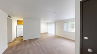Located in SeaTac, Washington, this 2-bedroom, 2-bathroom home offers a practical and comfortable single-floor layout. The open living room is bright and welcoming, featuring neutral carpet, clean white walls, and large windows with vertical blinds that invite generous natural light. Sliding glass doors lead to a private balcony, extending the living space outdoors. The galley-style kitchen is well-appointed with warm honey-toned wood cabinetry, white countertops, hardwood-style flooring, and white appliances including a gas range and refrigerator — offering ample storage and counter space. Both bedrooms are carpeted and feature large windows that bring in natural light, with the primary bedroom providing a comfortable, well-sized retreat. Three closets throughout the home offer excellent storage capacity. The two bathrooms are clean and functional: one features a full tub-shower combination, while the second includes a standalone shower stall, both with hardwood-style flooring. A hallway connects the rooms cohesively. The overall aesthetic is neutral and move-in ready, with a consistent palette of whites and warm wood tones throughout.