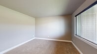 Located at 1108 E Thoroughbred Ln in Spokane, WA, this two-story home offers a thoughtfully organized layout across two floors. The main level features rich wood-look flooring throughout the open living and dining areas, a kitchen with a granite-topped breakfast bar accented by a modern pendant light, and a welcoming entryway with arched architectural detail and warm overhead lighting. The upper level is more expansive and houses all three bedrooms, three full bathrooms, and a dedicated laundry room complete with a side-by-side washer and dryer. The generously sized primary bedroom features a tray ceiling with recessed lighting, plush carpet, and direct access to a well-appointed en-suite bathroom. The primary bathroom includes a dual-sink vanity with dark wood cabinetry, white countertops, tile flooring, and a walk-in closet outfitted with wire shelving systems for organized storage. The additional bedrooms are carpeted and filled with natural light from window treatments. Each room is finished with clean white baseboards and neutral-toned walls, creating a cohesive and move-in-ready aesthetic throughout the home.