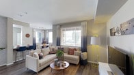This model unit at 8465 Regents Rd in San Diego offers a thoughtfully designed single-floor layout that blends comfort and contemporary style. The open-concept living and dining area serves as the heart of the space, where natural light pours in through large windows dressed with elegant ombre drapes, creating a warm and inviting ambiance. The living area features rich hardwood-style flooring that anchors the space, complemented by neutral-toned walls that lend a clean, modern aesthetic. A generously sized sectional sofa, a round wooden coffee table, and curated décor accents give the living space a welcoming, livable feel. Adjacent to the living room, the dining area provides a seamless transition for entertaining, with ample room for a full dining set. The layout is designed to maximize the sense of openness, with natural light from multiple windows brightening every corner. The overall ambiance is modern yet approachable, with a carefully curated combination of textures, tones, and furnishings that highlight the unit's potential. This model unit offers an excellent representation of the refined, comfortable lifestyle available at this San Diego address.