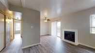 This single-floor residence presents a thoughtfully designed layout with consistent modern finishes throughout. The open living area serves as the heart of the home, showcasing wood-look luxury vinyl plank flooring, a textured ceiling, and a ceiling fan. A tile-surround fireplace anchors one wall, while a sliding glass door with vertical blinds floods the space with natural light and provides access to an outdoor area.

Adjacent to the living room, a secondary space features its own entrance with a classic six-panel door and connects seamlessly to the kitchen. The kitchen is well-equipped with white shaker-style cabinetry, grey speckled countertops, a stainless steel gas range, over-the-range microwave, refrigerator, and a double-basin sink beneath a window with plantation-style blinds.

The bedrooms are comfortable and bright, each featuring wood-look flooring, neutral grey walls, natural window light, and sliding or built-in closets with shelving for ample storage. The bathroom is clean and functional, outfitted with a tub-shower combination, white vanity cabinetry, grey countertops, brushed nickel hardware, and matching wood-look flooring. Overall, the space presents a cohesive, move-in-ready aesthetic with practical features throughout.