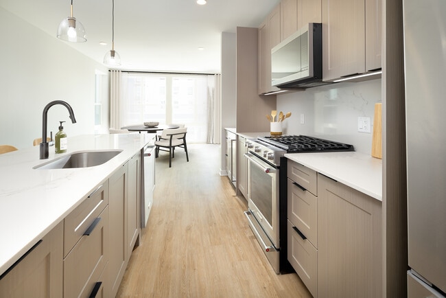 Signature Collection kitchen with oak shaker cabinetry, marbled white quartz countertop and backsplash, and upgraded stainless steel appliances - Avalon W Squared