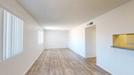 Located at 1975 W 36th St in Tucson, Arizona, this single-story unit offers a clean, functional layout with a consistently neutral palette throughout. Wood-look plank flooring runs through the living areas and bedrooms, providing a cohesive and low-maintenance finish underfoot. Textured ceilings add subtle visual depth to each room.

The open living area is well-proportioned and receives natural light through a window fitted with vertical blinds. A pass-through opening connects the living space to the kitchen, enhancing the sense of openness between the two areas. The kitchen is equipped with white cabinetry, a double-basin stainless steel sink, and granite-look countertops, offering practical workspace and storage.

The bedrooms are comfortably sized, each featuring windows with vertical blinds that allow for natural light and privacy control. The bright white walls and clean lines give each room a versatile, move-in-ready feel.

The bathroom includes a single-sink vanity with under-cabinet storage, a full tub-shower combination, and wood-look flooring that ties in with the rest of the unit. A ventilation fan and overhead lighting complete the space. Central HVAC vents are present throughout, ensuring year-round climate comfort in the Tucson desert environment.