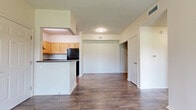 This single-story 2-bedroom, 2-bathroom unit offers a practical and comfortable layout designed for everyday living. The open-concept living and dining area features rich wood-style flooring, neutral walls, and a ceiling fan with direct access to a sliding glass door that opens to an outdoor view, filling the space with natural light. The adjacent kitchen is efficiently designed with light maple cabinetry, dark granite-style countertops, a breakfast bar, and a full suite of black appliances including a range, refrigerator, and dishwasher. A window above the sink adds natural light to the workspace. Both bedrooms are carpeted and feature ceiling fans and windows that bring in natural light and outdoor views. The primary bedroom is a comfortable size and is paired with a dedicated closet outfitted with wire shelving systems offering generous storage. The two bathrooms are consistent in design, each featuring light wood cabinetry, dark countertops, a single vanity with a large mirror, and wood-style flooring. One bathroom includes a full soaking tub and shower combination. A hallway connects the bedrooms and bathrooms, maintaining a clear and logical flow throughout the unit. A dedicated closet and in-unit laundry connections round out the functional amenities of this well-organized home.
