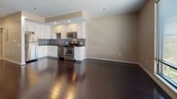 Located at 26-44 Front St in downtown Hartford, Connecticut, this single-floor unit offers a thoughtfully designed open-concept layout that maximizes both functionality and visual flow. Rich, dark hardwood flooring extends throughout the main living areas, creating a polished and cohesive aesthetic that anchors the space.

The kitchen is a standout feature, outfitted with white cabinetry that reaches toward the ceiling, providing generous storage. Dark granite countertops contrast sharply against the cabinetry, while a textured mosaic tile backsplash adds depth and visual interest. A full suite of stainless steel appliances — including a refrigerator, dishwasher, gas range, and microwave — ensures a well-equipped cooking environment. The layout connects seamlessly to the open living area, making it ideal for entertaining.

The living space is generously proportioned, with warm neutral-toned walls and recessed lighting lending a clean, contemporary feel. A hallway leads to multiple closets, offering substantial storage capacity throughout. The bathroom features large-format tile flooring, a dark-stained vanity with a framed mirror, and a clean, functional design that complements the overall aesthetic of the unit.
