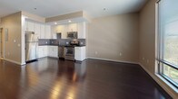 Located at 26-44 Front St in downtown Hartford, Connecticut, this single-floor unit offers a thoughtfully designed open-concept layout that maximizes both functionality and visual flow. Rich, dark hardwood flooring extends throughout the main living areas, creating a polished and cohesive aesthetic that anchors the space.

The kitchen is a standout feature, outfitted with white cabinetry that reaches toward the ceiling, providing generous storage. Dark granite countertops contrast sharply against the cabinetry, while a textured mosaic tile backsplash adds depth and visual interest. A full suite of stainless steel appliances — including a refrigerator, dishwasher, gas range, and microwave — ensures a well-equipped cooking environment. The layout connects seamlessly to the open living area, making it ideal for entertaining.

The living space is generously proportioned, with warm neutral-toned walls and recessed lighting lending a clean, contemporary feel. A hallway leads to multiple closets, offering substantial storage capacity throughout. The bathroom features large-format tile flooring, a dark-stained vanity with a framed mirror, and a clean, functional design that complements the overall aesthetic of the unit.