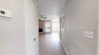 Located at 1030 Douglas Avenue in Altamonte Springs, Florida, this single-story residence offers a thoughtfully laid-out floor plan with a clean, neutral aesthetic throughout. Light wood-style flooring flows continuously across the main living areas and bedrooms, complemented by soft gray walls and white trim that create a bright, cohesive interior.

The living room serves as the centerpiece of the home, highlighted by a full-height brick fireplace that anchors the space with warmth and character. A ceiling fan overhead and multiple windows with blinds allow for natural light and comfortable airflow. The open layout provides generous room for a variety of furniture arrangements.

The kitchen is well-appointed with white cabinetry, light stone-look countertops, a double-basin sink, a stainless steel refrigerator, a dishwasher, and an electric range. A window above the sink brings in natural light, and the light flooring ties the kitchen seamlessly to the rest of the home.

Additional rooms include well-sized bedrooms with ceiling fans and ample natural light via exterior-facing windows. The bathroom features a full tub-shower combination with white tile surround. A standout feature is the walk-in closet, which includes built-in shelving and wraparound hanging rods, offering excellent storage capacity. The textured ceilings are consistent throughout the home.