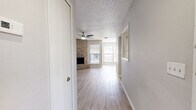 Located at 1030 Douglas Avenue in Altamonte Springs, Florida, this single-story residence offers a thoughtfully laid-out floor plan with a clean, neutral aesthetic throughout. Light wood-style flooring flows continuously across the main living areas and bedrooms, complemented by soft gray walls and white trim that create a bright, cohesive interior.

The living room serves as the centerpiece of the home, highlighted by a full-height brick fireplace that anchors the space with warmth and character. A ceiling fan overhead and multiple windows with blinds allow for natural light and comfortable airflow. The open layout provides generous room for a variety of furniture arrangements.

The kitchen is well-appointed with white cabinetry, light stone-look countertops, a double-basin sink, a stainless steel refrigerator, a dishwasher, and an electric range. A window above the sink brings in natural light, and the light flooring ties the kitchen seamlessly to the rest of the home.

Additional rooms include well-sized bedrooms with ceiling fans and ample natural light via exterior-facing windows. The bathroom features a full tub-shower combination with white tile surround. A standout feature is the walk-in closet, which includes built-in shelving and wraparound hanging rods, offering excellent storage capacity. The textured ceilings are consistent throughout the home.