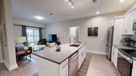 Located at 77 Gardnertown Rd in Newburgh, NY, this single-floor residence offers a thoughtfully designed open-concept layout with modern finishes throughout. Light-toned luxury vinyl plank flooring runs through the main living areas, creating a cohesive and clean aesthetic.

The kitchen serves as a central focal point, anchored by a large island with a quartz countertop, an undermount sink, and seating for casual dining. White shaker cabinetry pairs with stainless steel appliances, including a refrigerator, range, microwave, and dishwasher, while subway tile backsplash adds a classic touch. Track and recessed lighting illuminate the space effectively.

The kitchen flows seamlessly into the living area, which features a sliding glass door that connects to an outdoor space and allows natural light to fill the room. A separate dining area is conveniently positioned near an in-unit stacked washer and dryer.

The two bedrooms each offer natural light through large windows with neutral-toned walls and ample space. The bathrooms are well-appointed, with one featuring a spacious walk-in shower with white subway tile, a built-in bench, glass doors, and dark vanity cabinetry — delivering a clean, contemporary design.